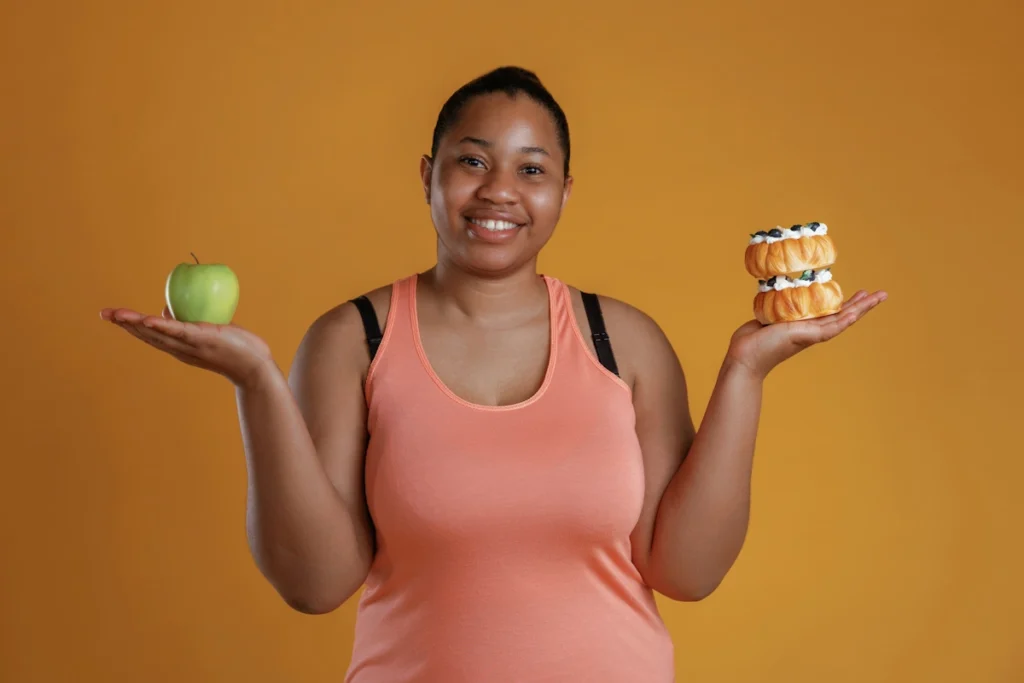 Une femme qui tient une pomme dans sa main et des pâtisseries dans l'autre