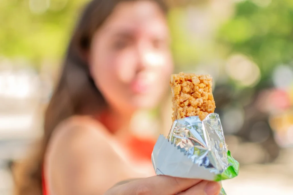 Une femme qui tient une barre de Collation protéinée sucrée
