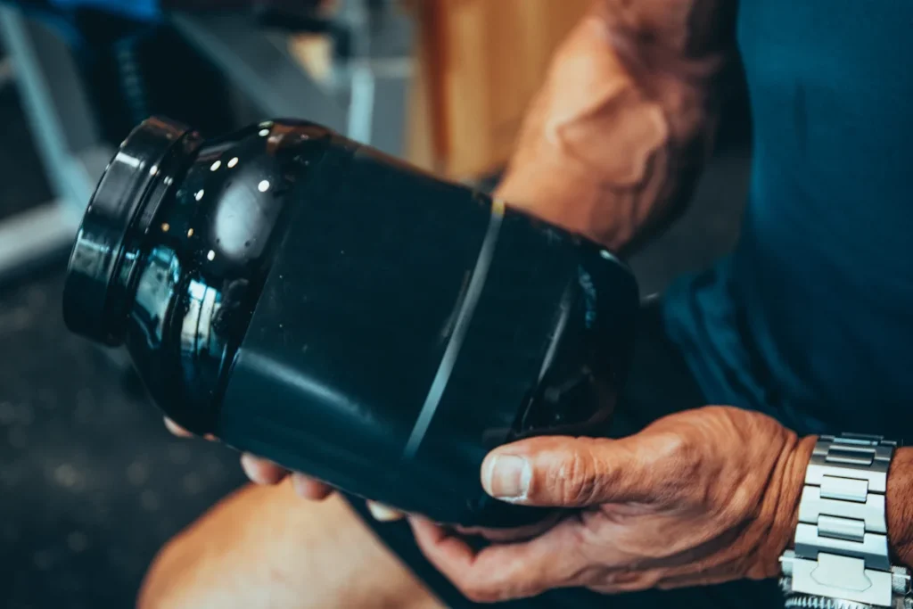 Un sportif qui tient une boîte de protéine